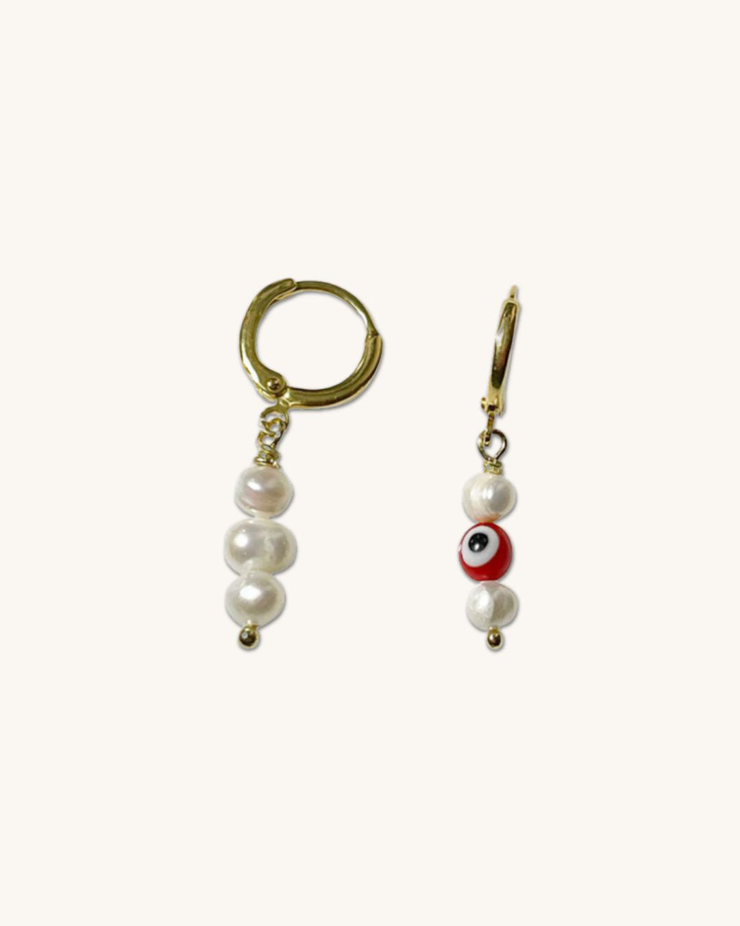 The Evil Eye Pearl Hoop Earrings, a pair of gold huggie hoops earrings featuring freshwater pearls.