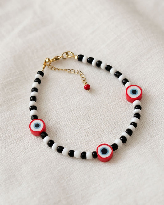 A black & white beaded anklet with red evil eye beads