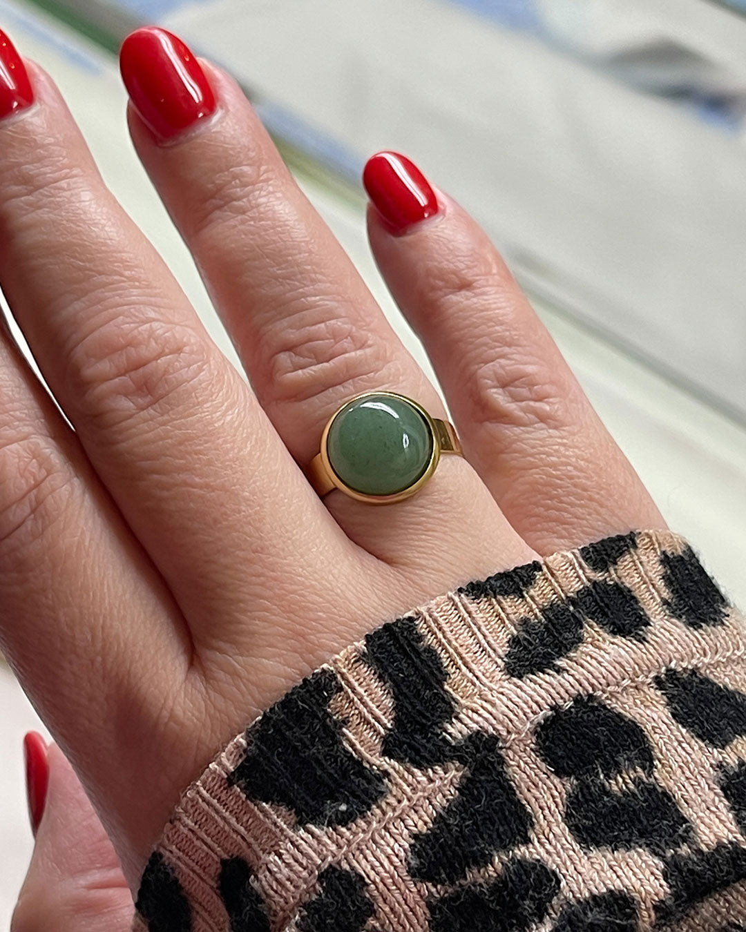 Hand wearing a gold waterproof adjustable band ring with an aventurine stone