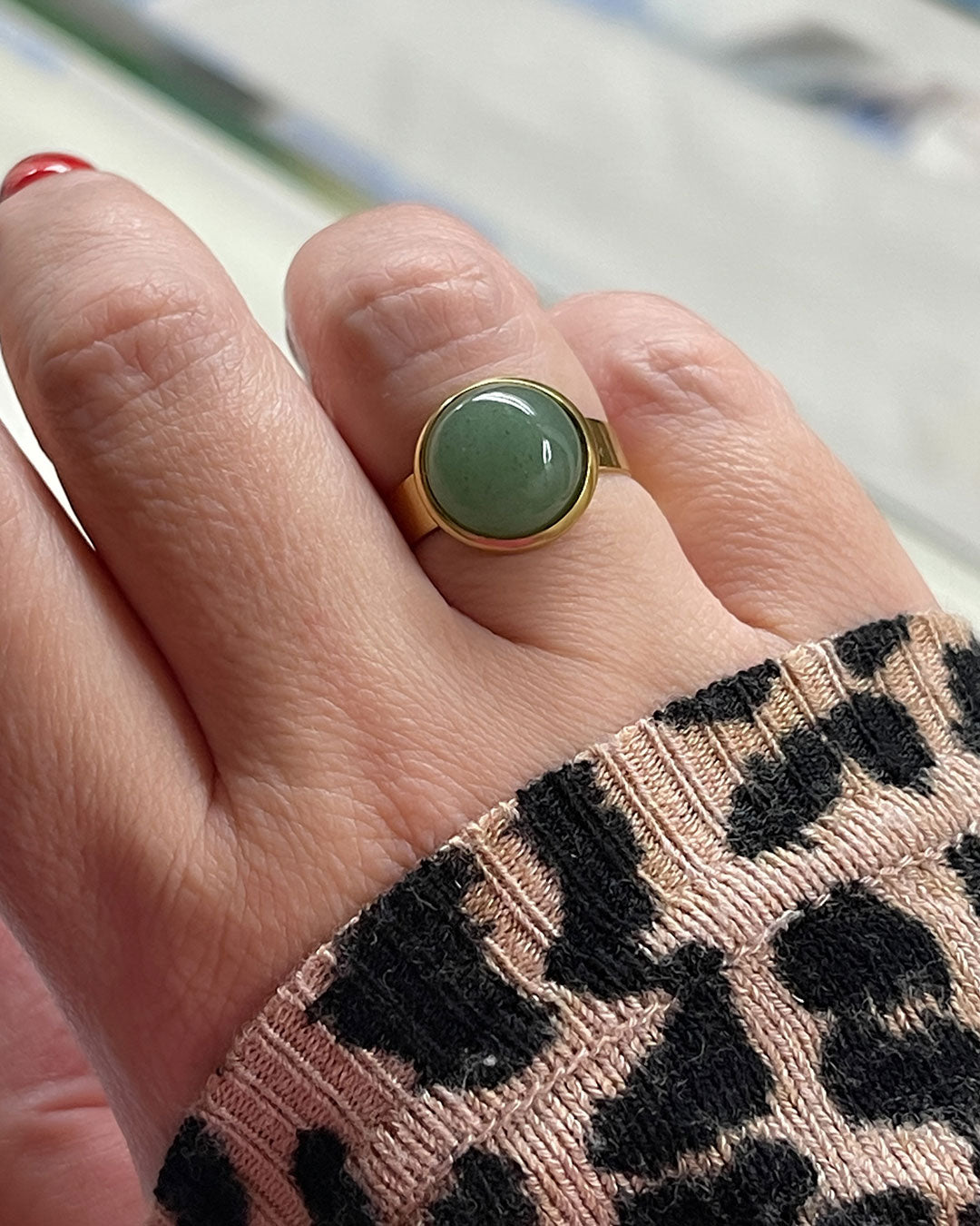Hand wearing a gold waterproof adjustable band ring with an aventurine stone