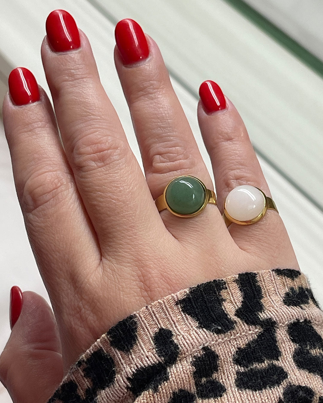 Hand wearing two gold waterproof adjustable band ring with an aventurine and a rose quartz stone