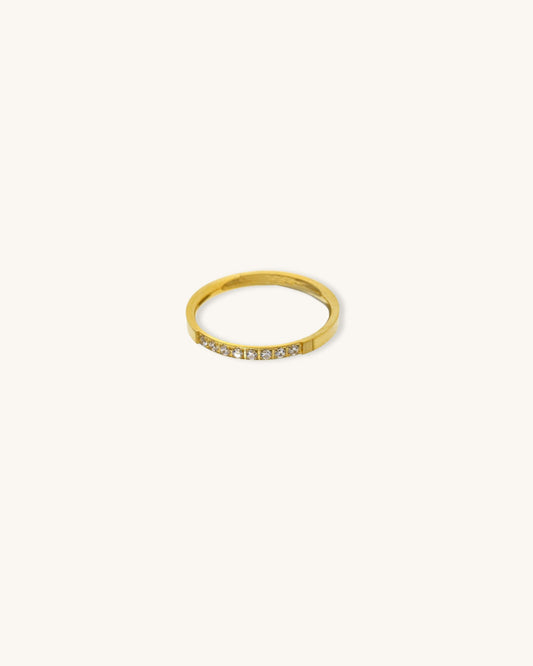 A waterproof gold band ring with diamonds on a neutral background