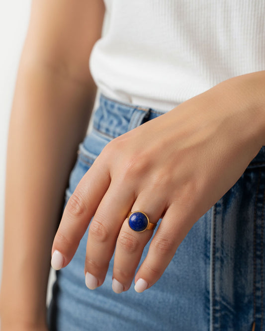 Hand wearing a gold waterproof adjustable band ring with a lapis lazuli stone