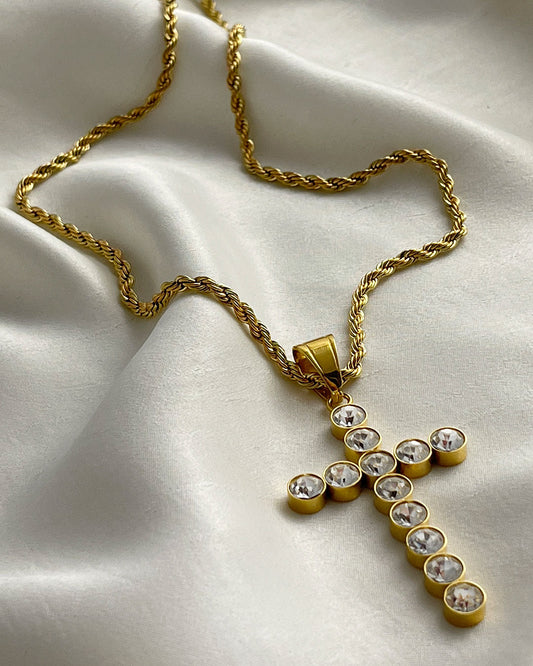 A gold chain necklace with a gold cross pendant. The cross is adorned with clear round crystals.