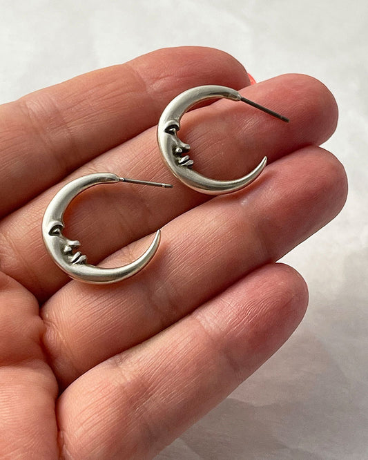 The Crescent Moon Earrings, a pair of half-moon-shaped silver earrings