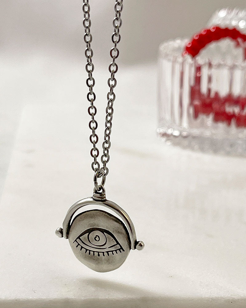 A silver necklace with an eye pendant. The pendant is round and has a detailed eye design.
