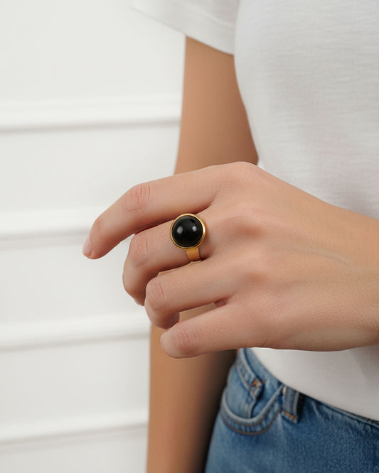 Hand wearing a black onyx ring in gold