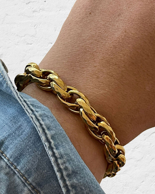 Gold chunky braided chain bracelet on a wrist against a white background