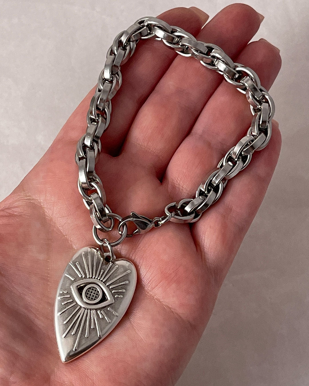 A close-up look of our evil eye heart charm bracelet with a silver chunky chain