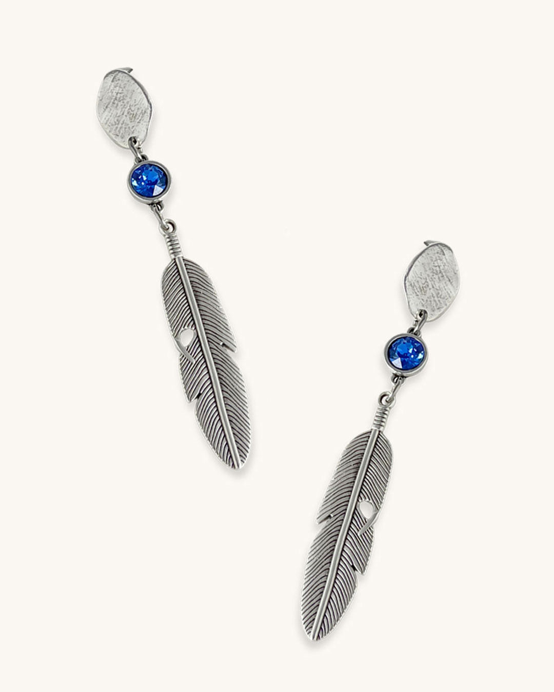 A pair of silver feather earrings with a blue Swarovski crystal. Each earring features a textured silver feather charm dangling from silver oval-shaped studs. The earrings have a bohemian style and are suitable for adding a touch of elegance to any outfit.