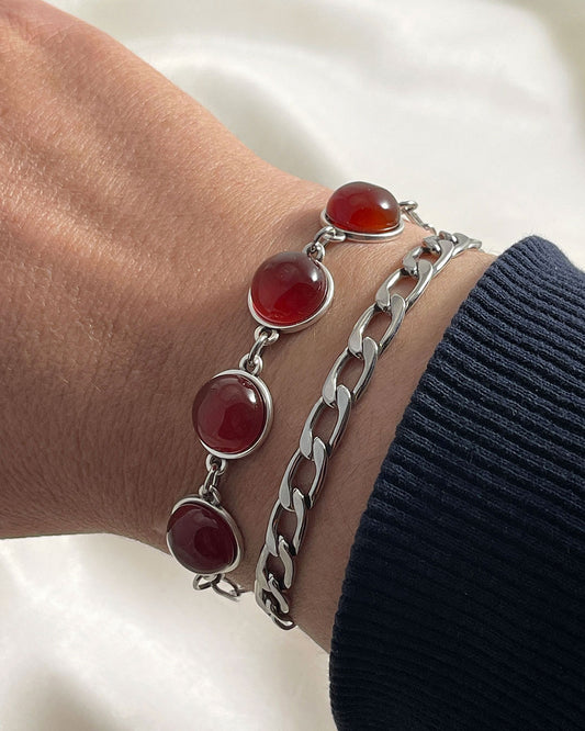 Two silver bracelets stacked: one paperclip chain with carnelian gemstones, and one curb chain bracelet. A modern jewelry set.