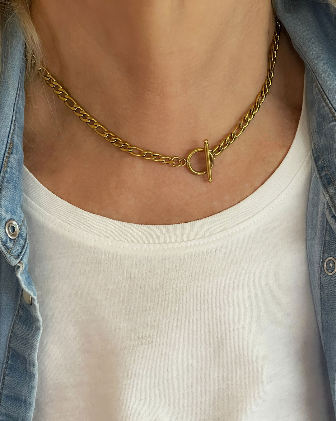 Model wearing a figaro chain necklace in gold with a toggle clasp closure