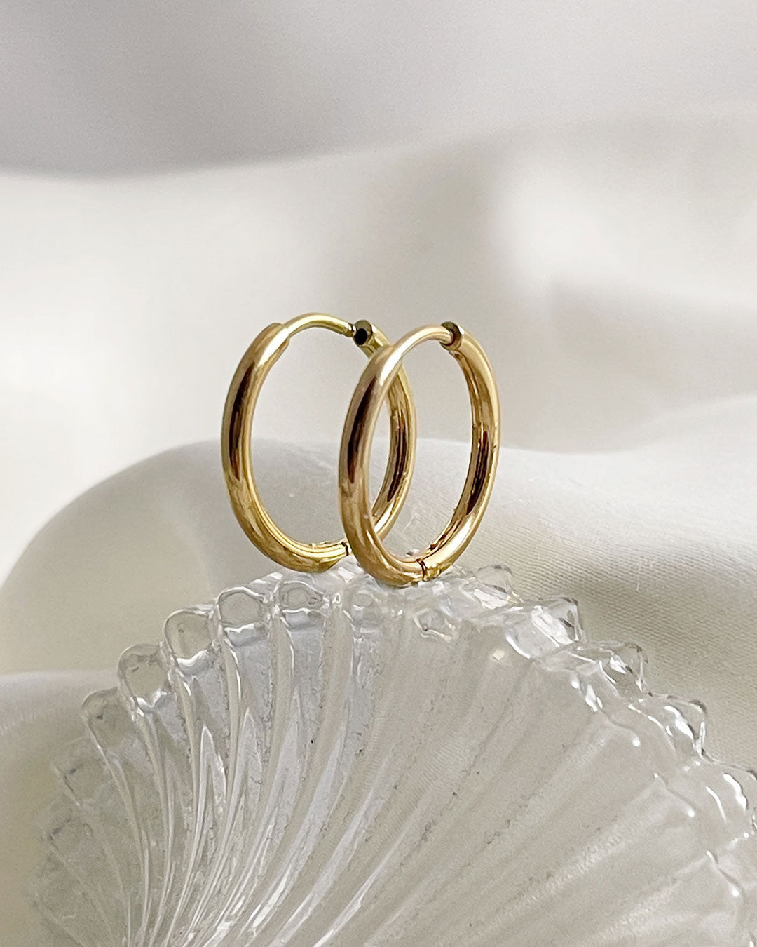 Gold hoop earrings 14mm on a white shell