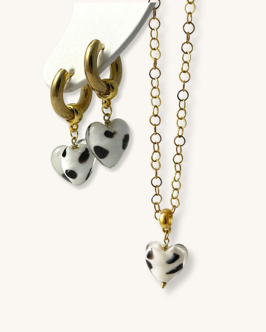 The Heart Bundle is a gold hoop earring with black and white heart charm and a gold necklace with a matching pendant