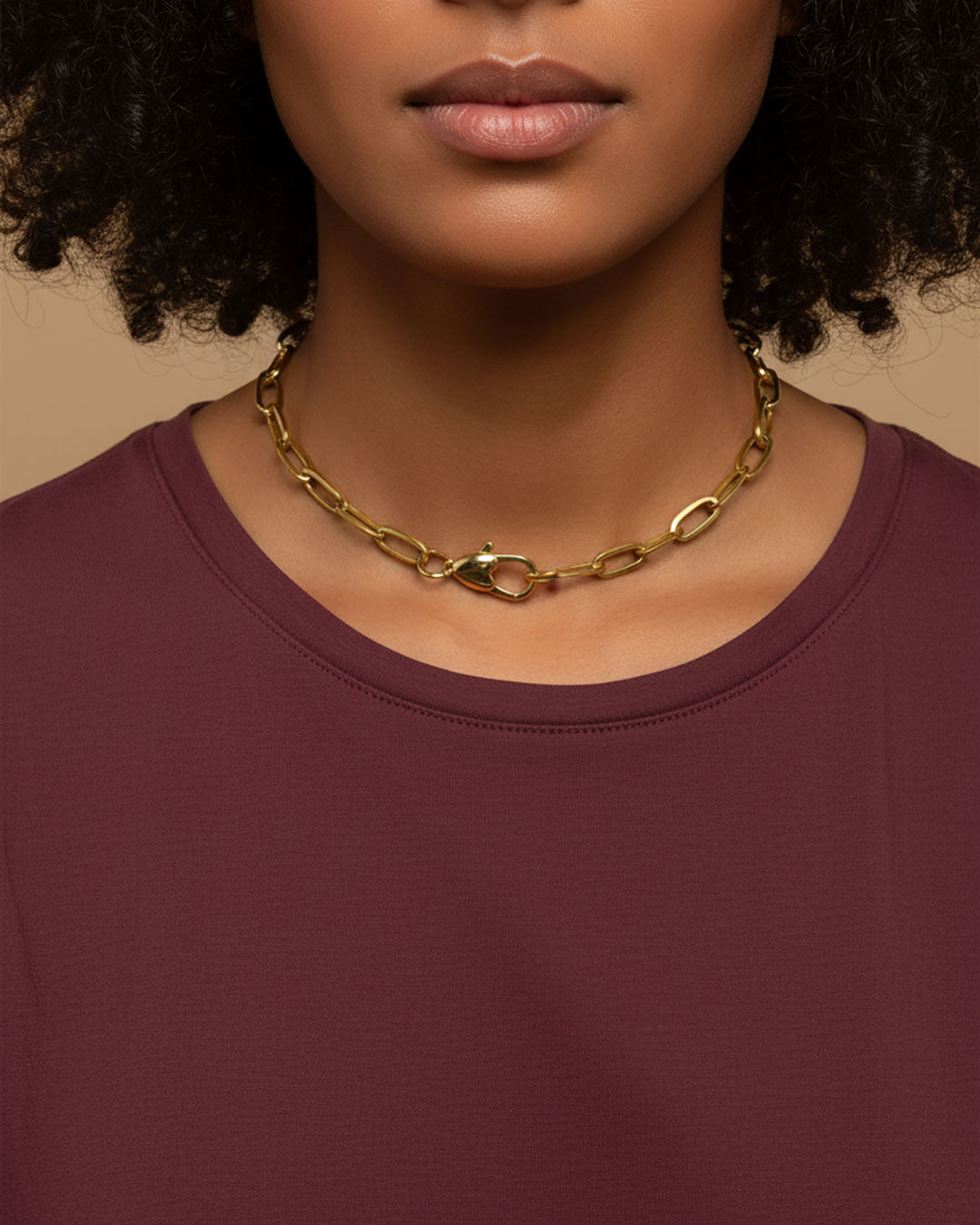 Model wearing a gold chain necklace with a heart shaped closure