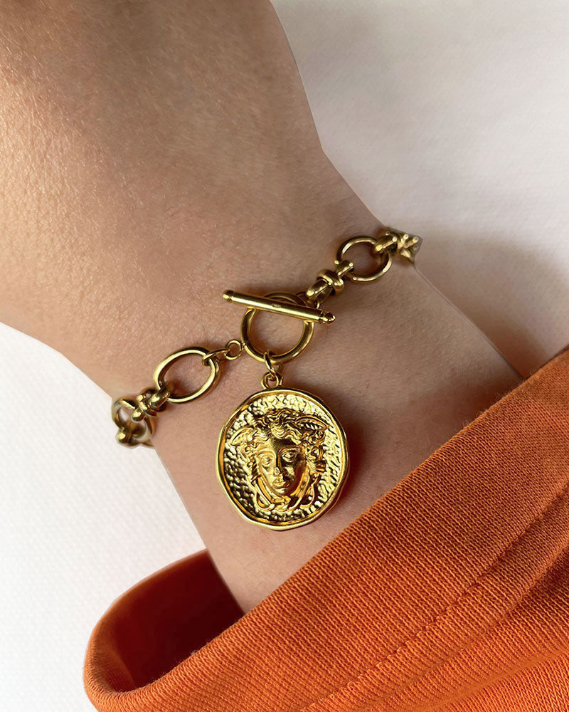 A Chunky Gold Link Chain Medusa Charm Bracelet on a wrist