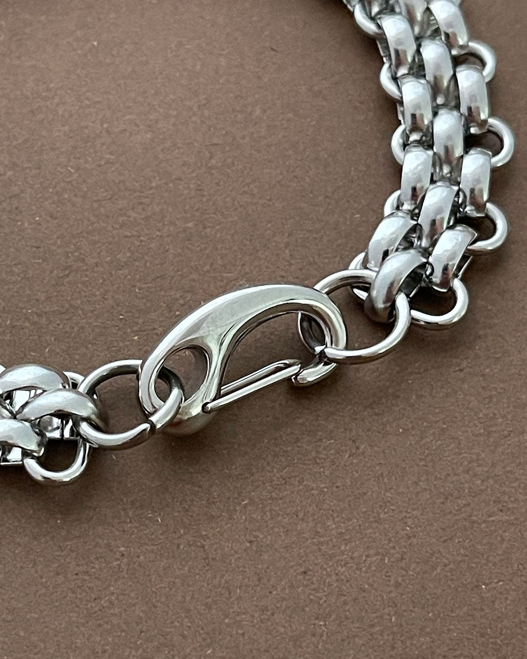 Close-up of a "Palmer" silver chain bracelet on a brown background