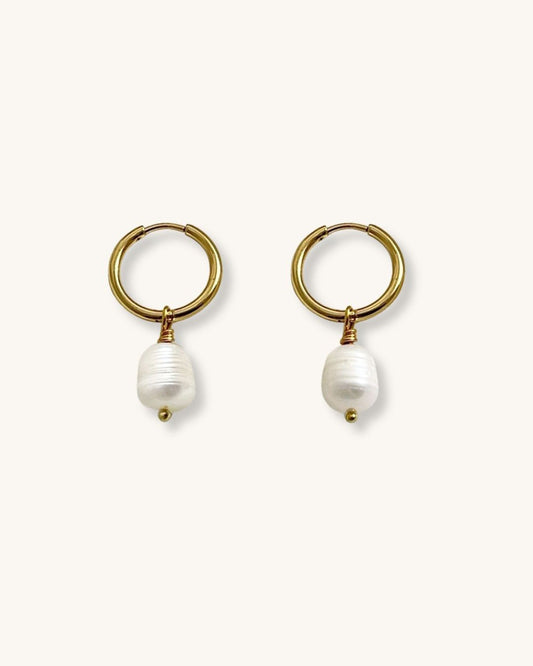 Gold hoop earrings with real pearls on a white background