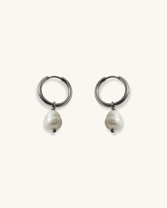 Pair of silver hoop earrings with real pearls on a white background