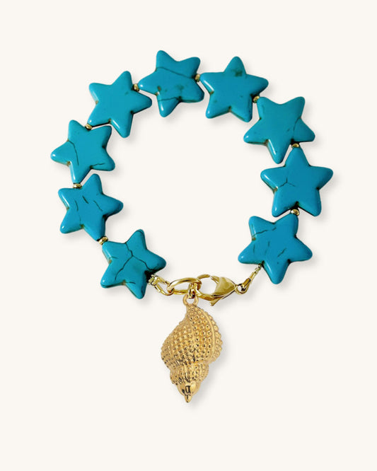 Turquoise star-shaped bracelet with a gold shell charm on a natural background