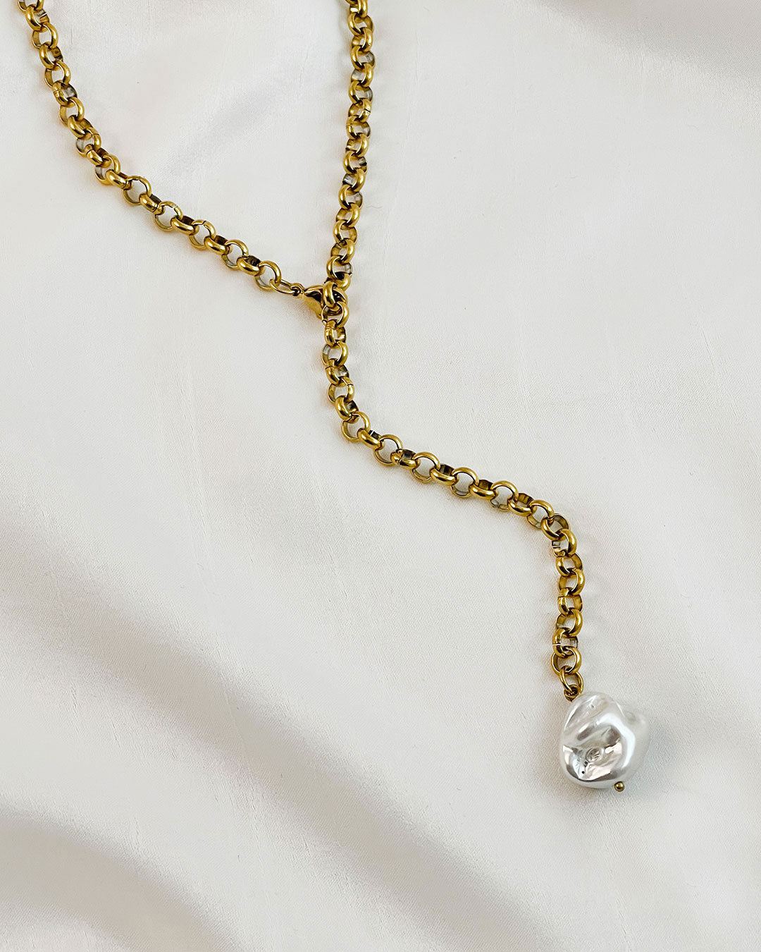 Gold chain necklace with a mop shell pearl pendant on a white background