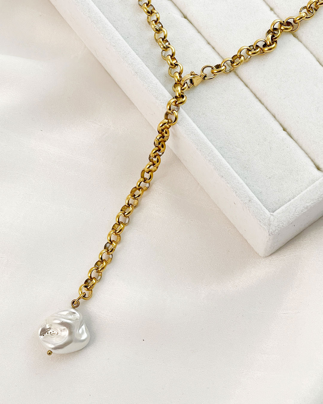 Gold chain necklace with a MOP pearl pendant on a white surface