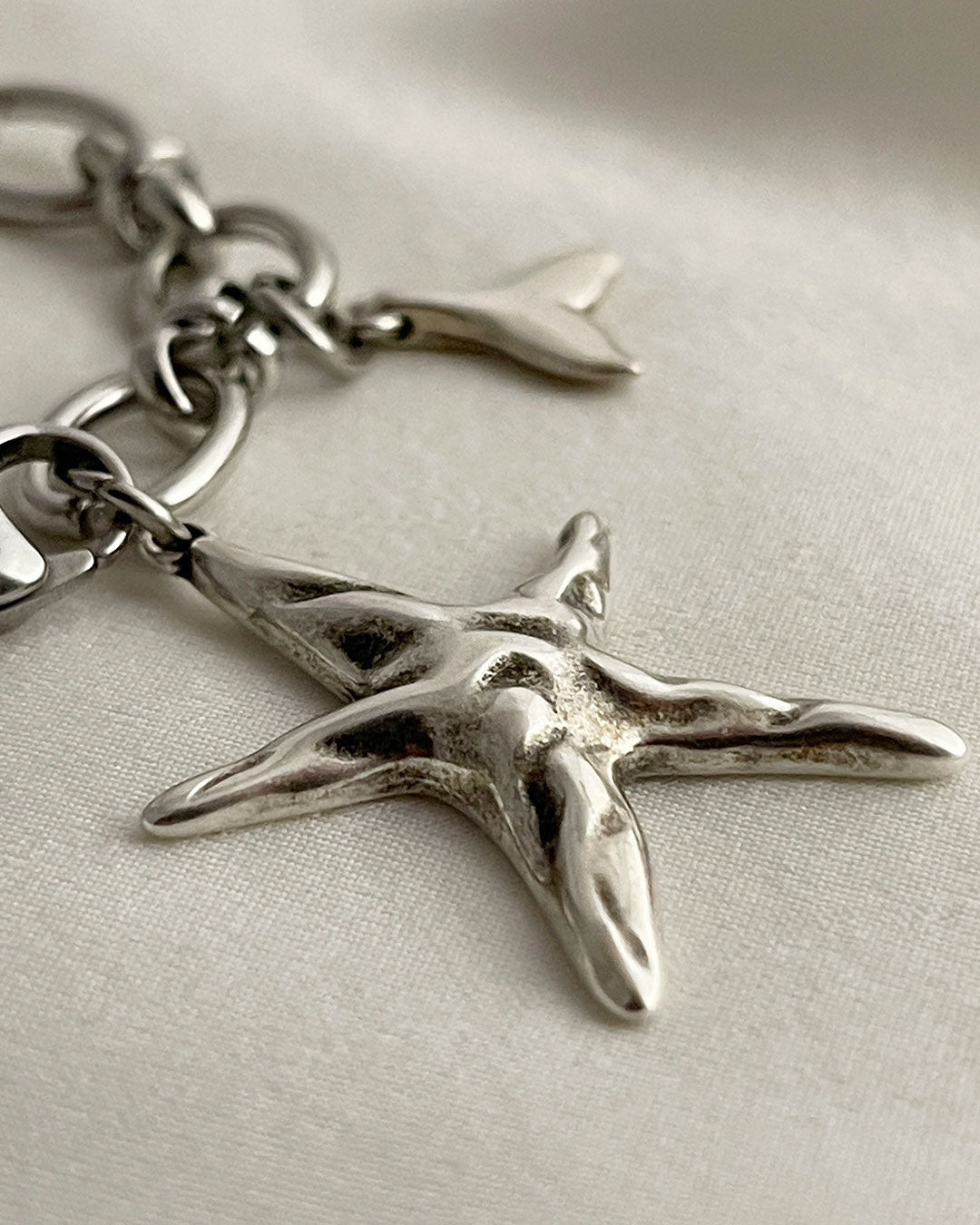 Silver starfish charm on a chain against a light background