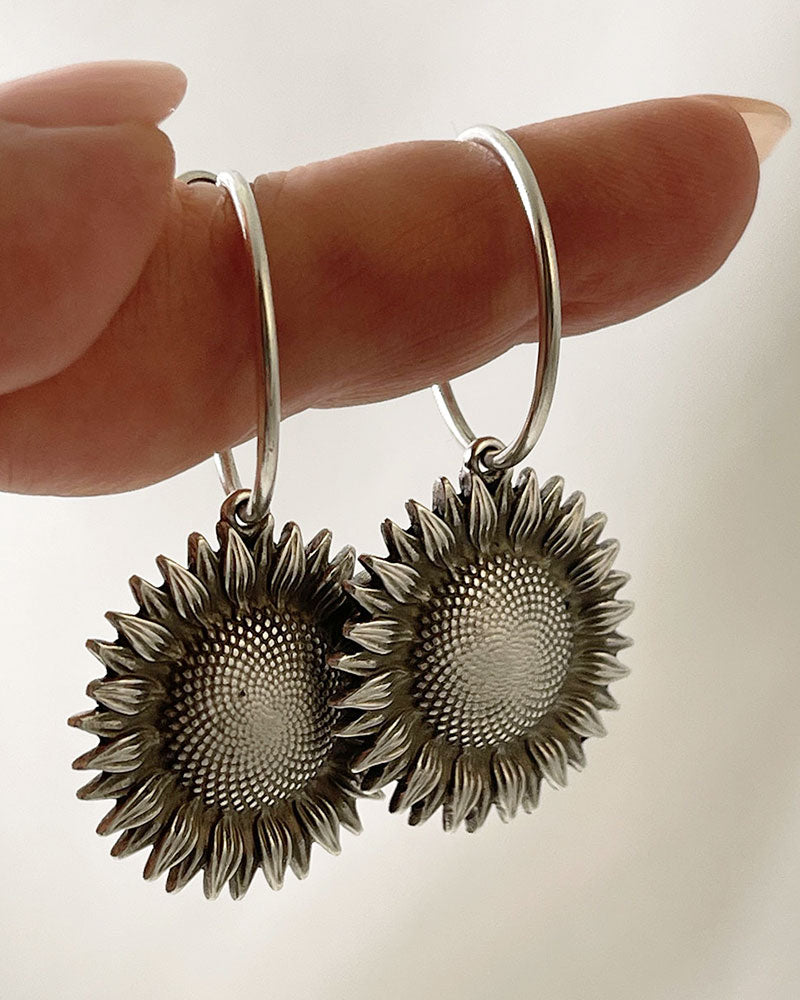 The Sunflower Hoop Earrings, a pair of silver hoop earrings featuring a sunflower charm.