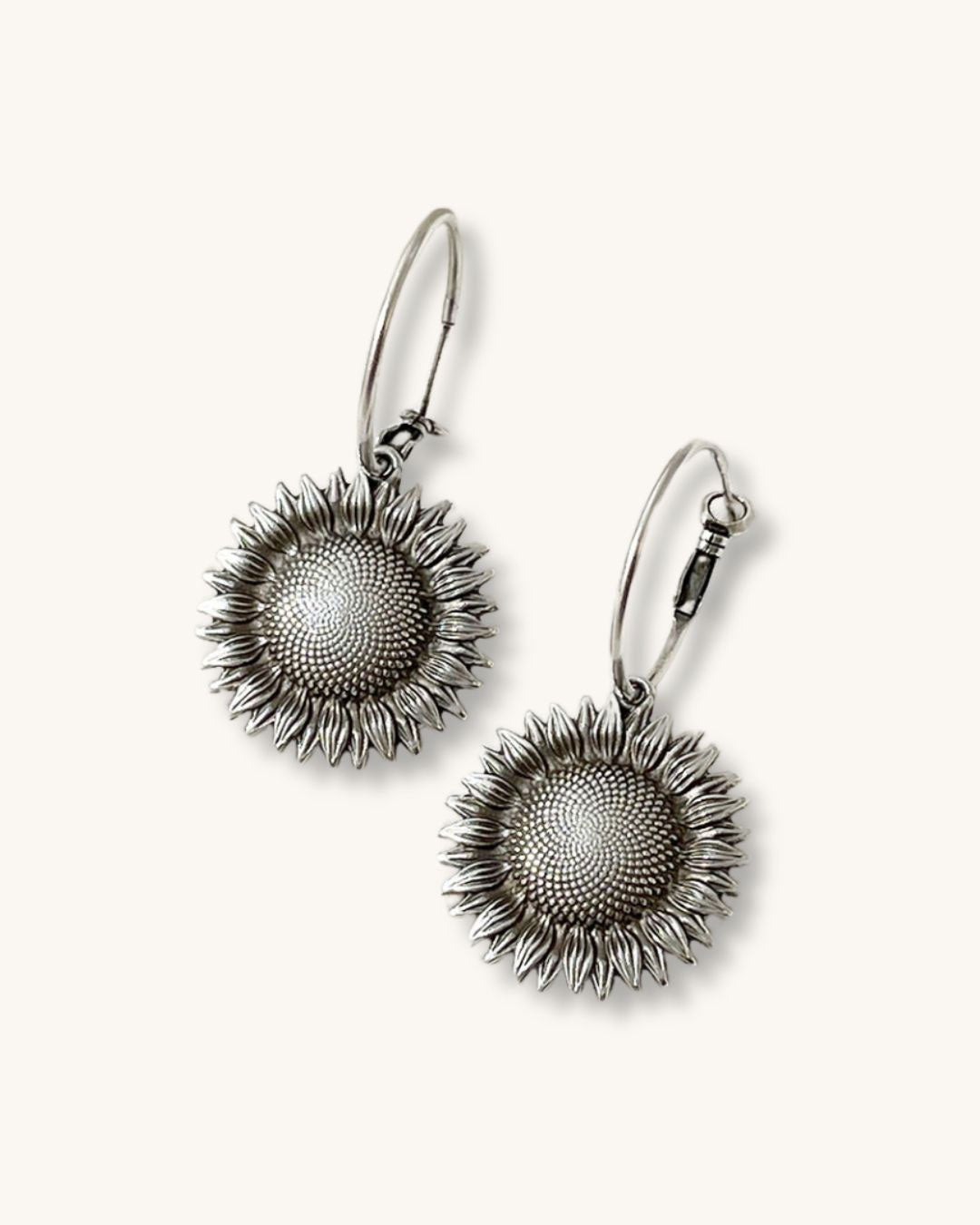 The Sunflower Hoop Earrings, is a pair of silver hoop earrings featuring a sunflower charm.
