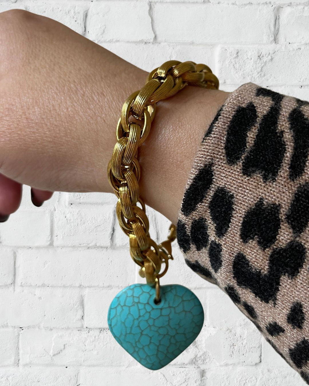 A gold chunky chain bracelet with a large turquoise gemstone heart charm