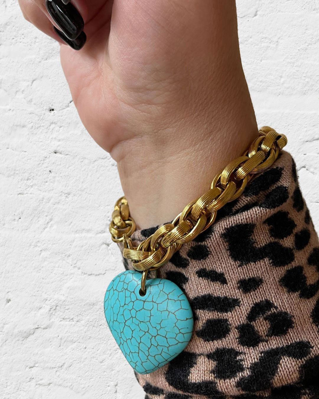 A gold chunky chain bracelet with a large turquoise gemstone heart charm