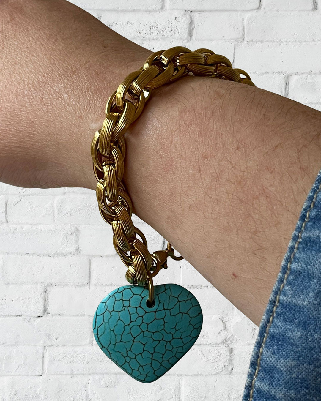 A gold chunky chain bracelet with a large turquoise gemstone heart charm