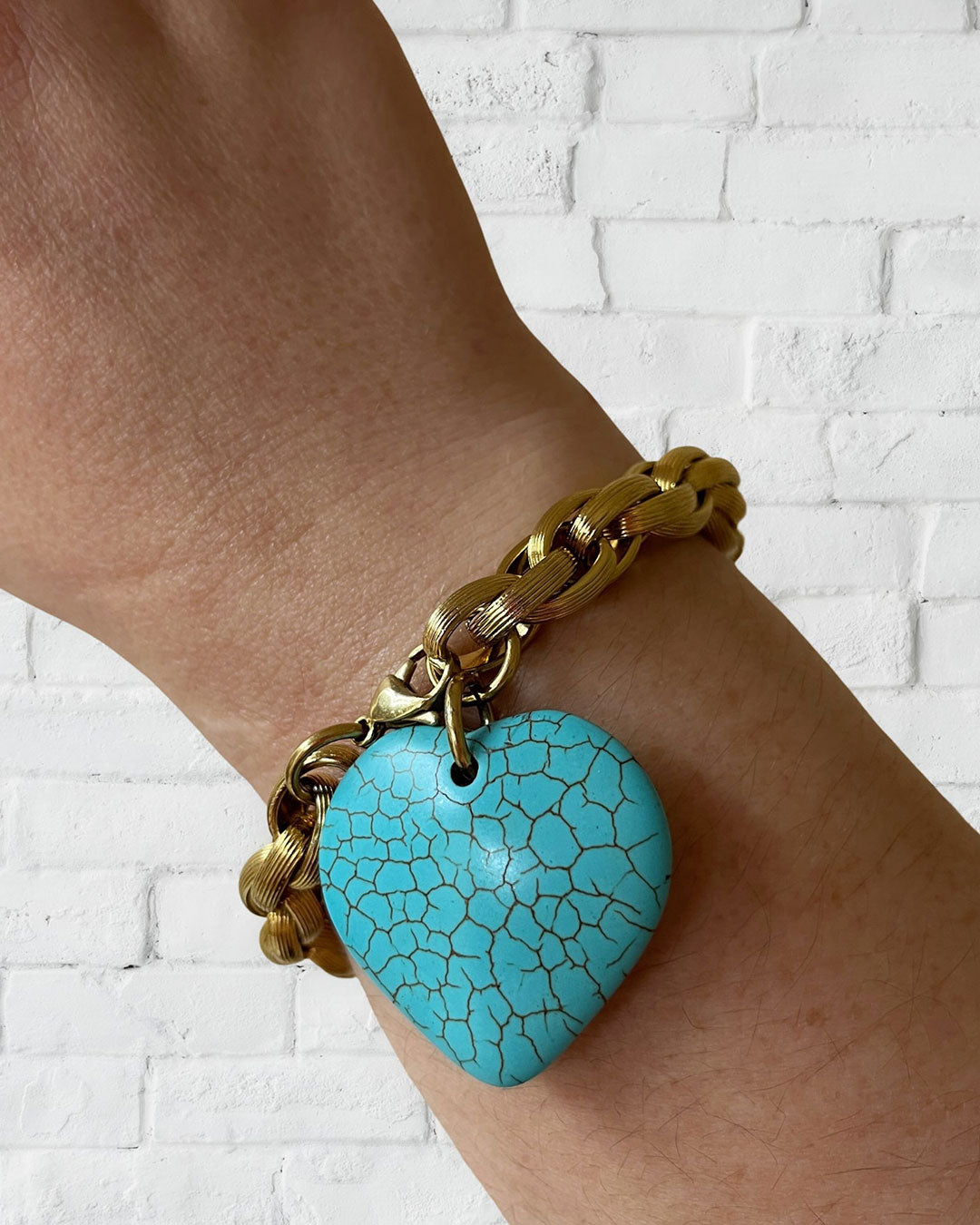 A gold chunky chain bracelet with a large turquoise gemstone heart charm