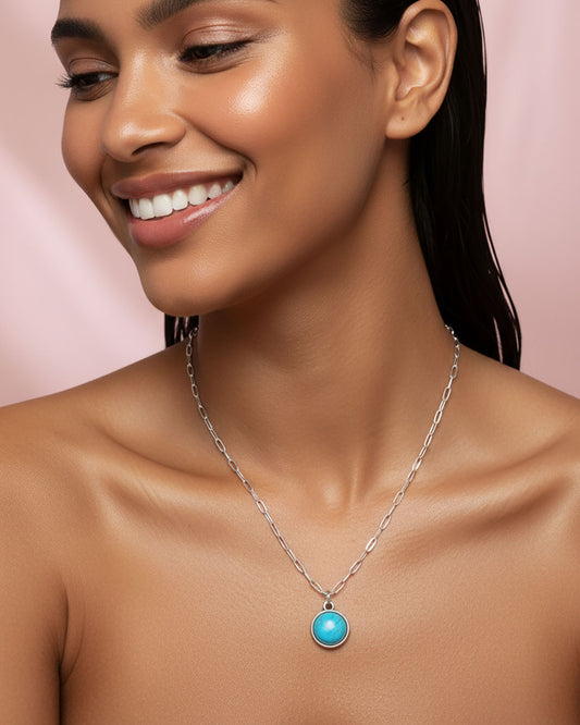 Woman wearing a silver paperclip chain necklace with a turquoise pendant