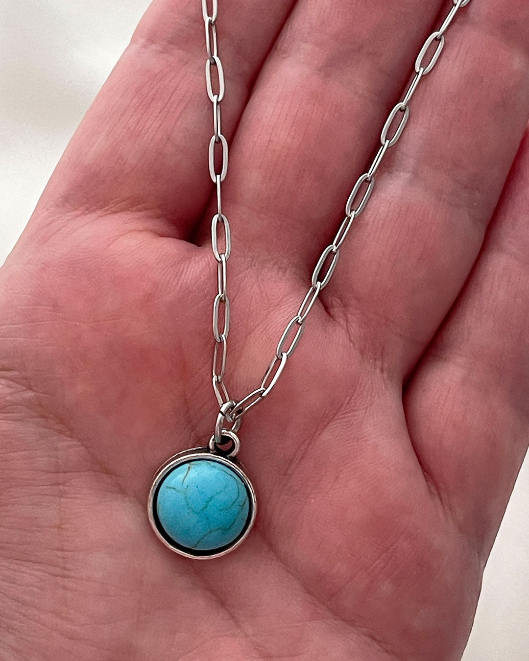 Turquoise pendant necklace on a hand