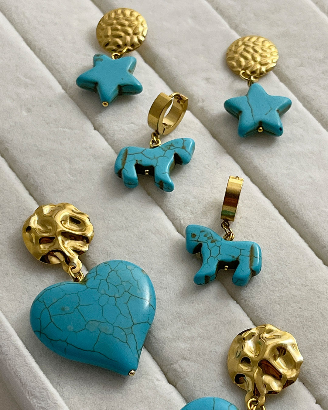 Turquoise and gold earrings on a textured surface