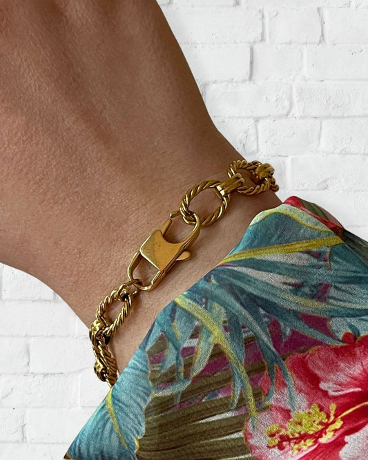 Wrist with a gold chain bracelet with twisted links and a clasp closure