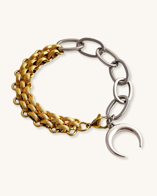 Bracelet with gold and silver chain links and a moon charm on a light background