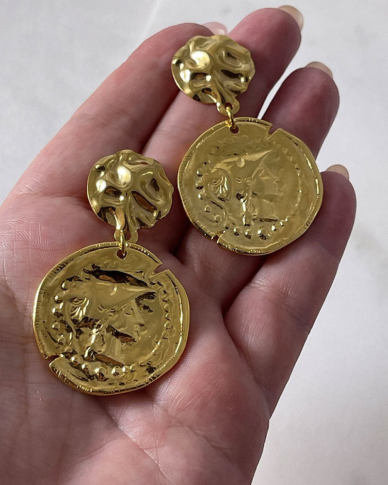 The Athena Coin Earrings, a pair of gold earrings featuring a raised design of Athena's goddess face accents on a coin.