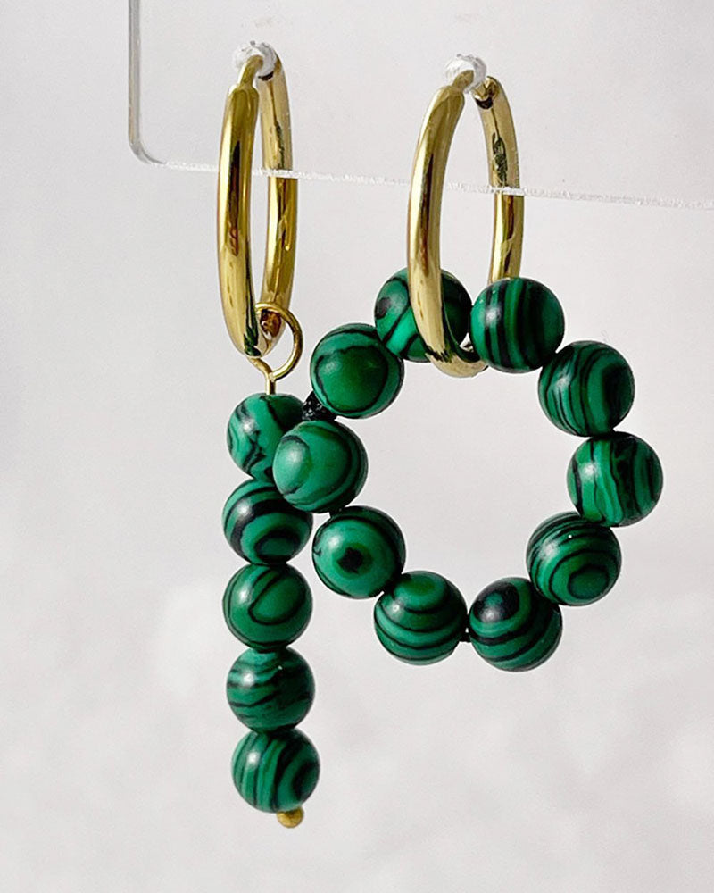 The Malachite Hoop Earrings, a pair of gold hoop earrings featuring malachite stones.