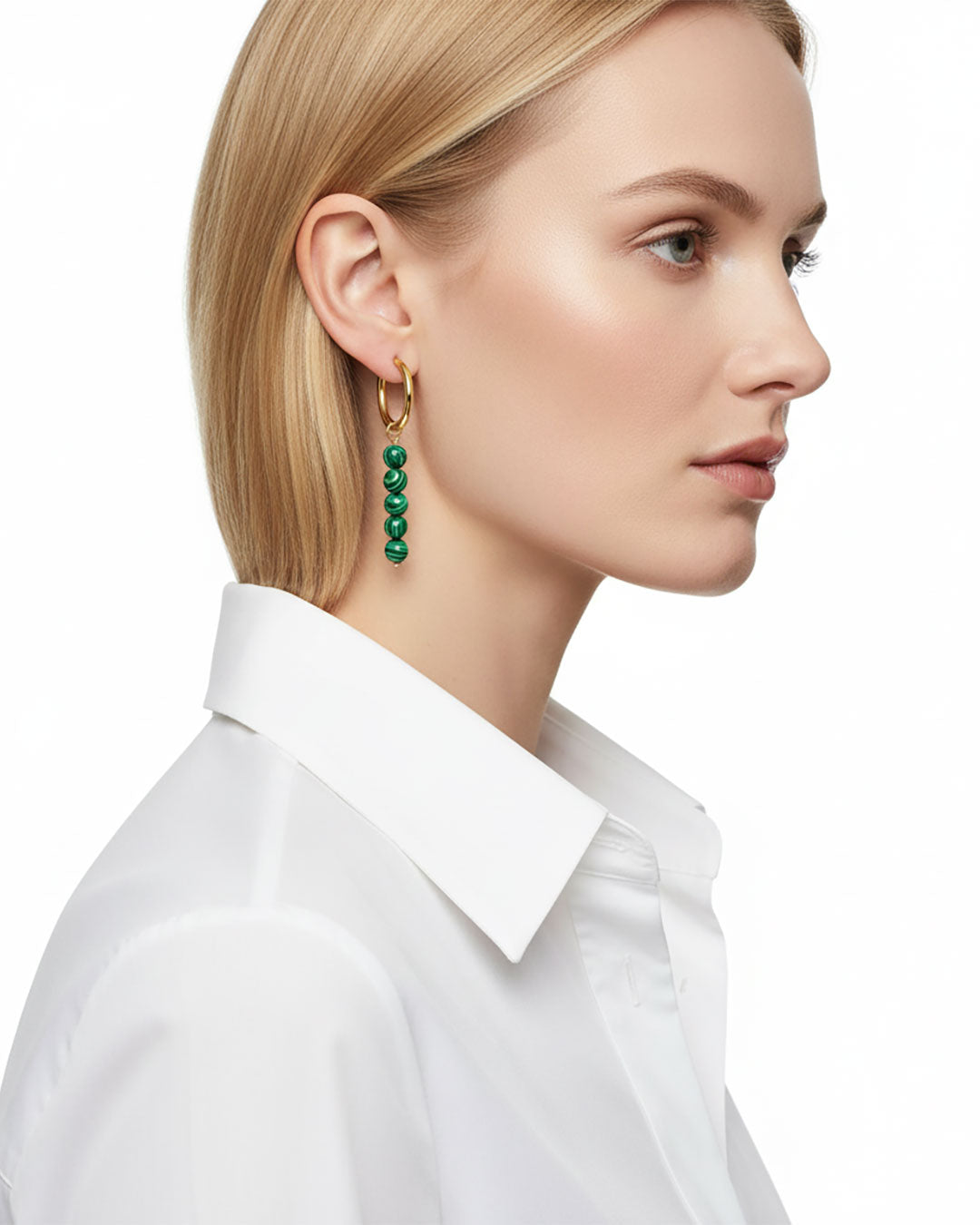 Model wearing gold hoop earrings with malachite green beads