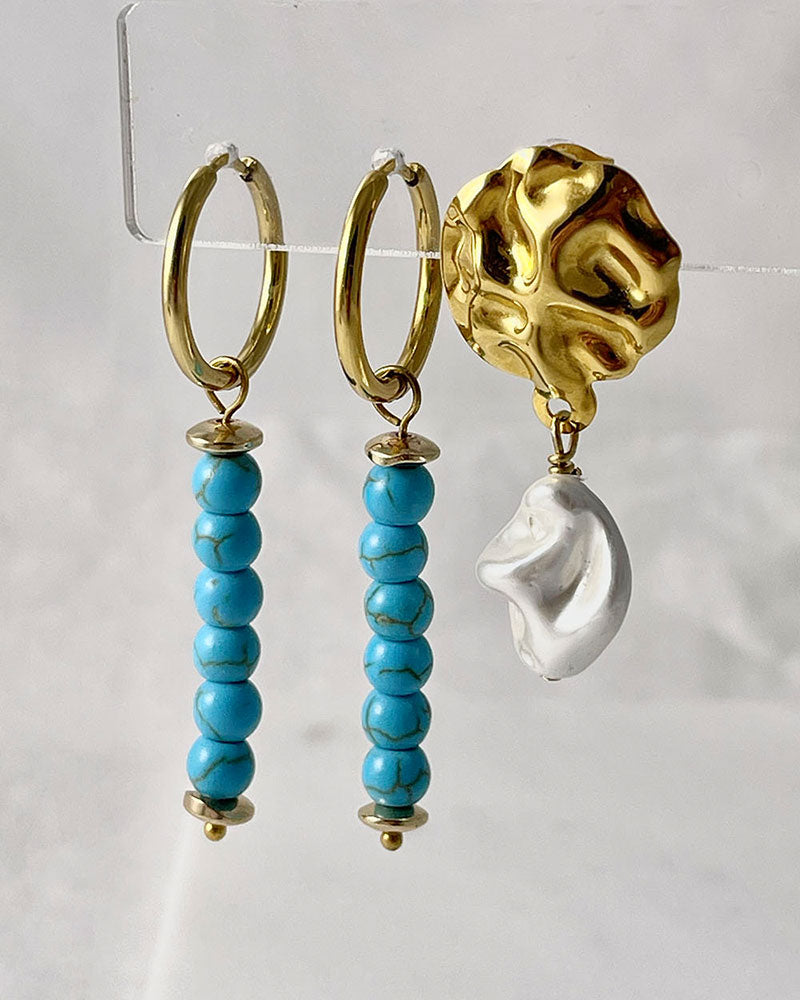 The Turquoise Gem Hoop Earrings, a pair of gold hoop earrings featuring turquoise howlite stones.