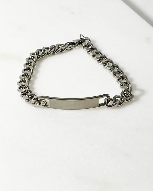A chunky curb chain bracelet in silver connected by a solid bar at the center.
