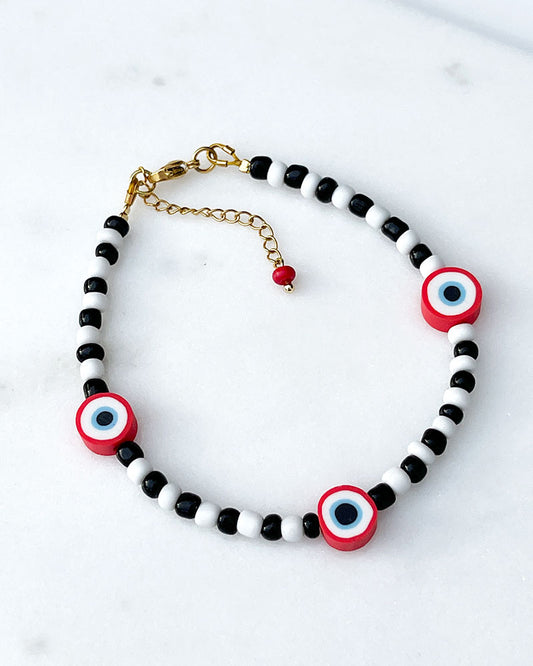 A black & white beaded anklet with red evil eye beads