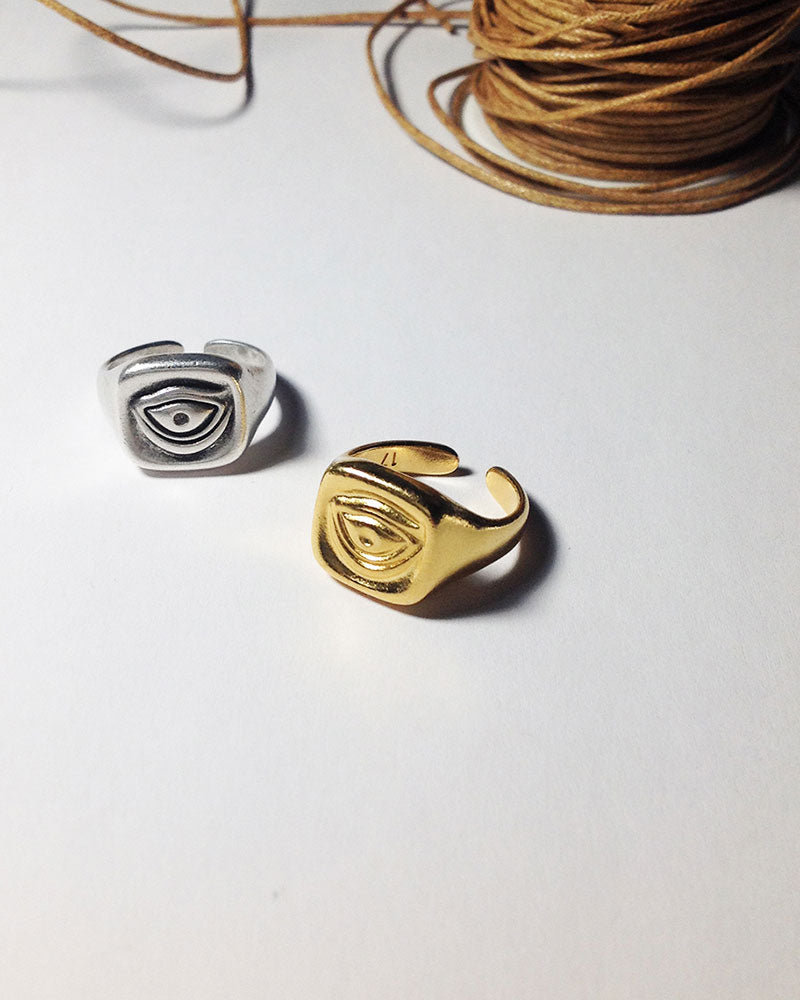 Gold and silver rings with an eye design, displayed on a white surface