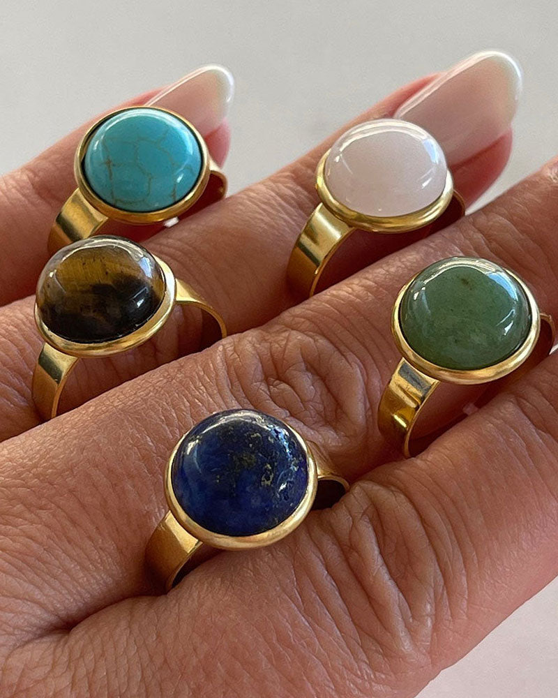 Hand wearing gold adjustable waterproof rings with different gemstones