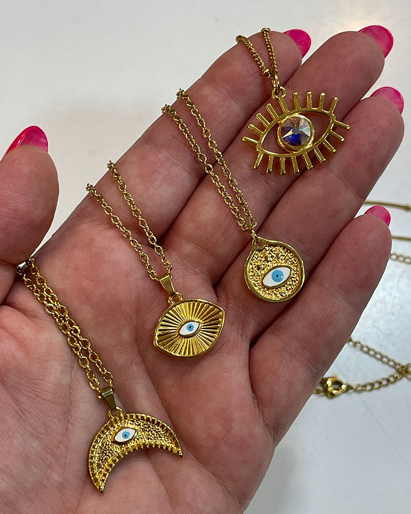 A dainty chain necklace with a small round pendant. The pendant is gold with a white blue enamel evil eye design.