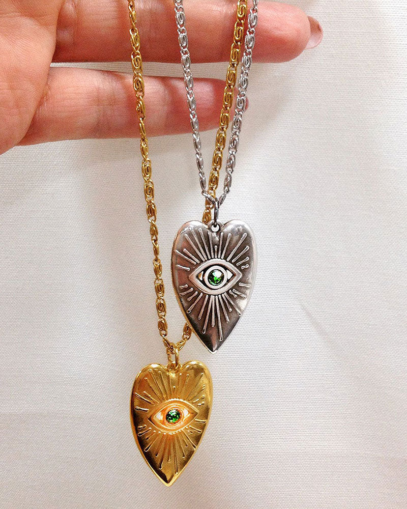 Evil eye heart pendant necklace adorned with an emerald Swarovski crystal in the middle of the eye and a long stainless steel chain.