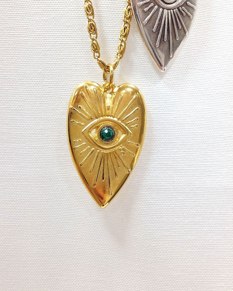 Evil eye heart pendant necklace adorned with an emerald Swarovski crystal in the middle of the eye and a long stainless steel chain.