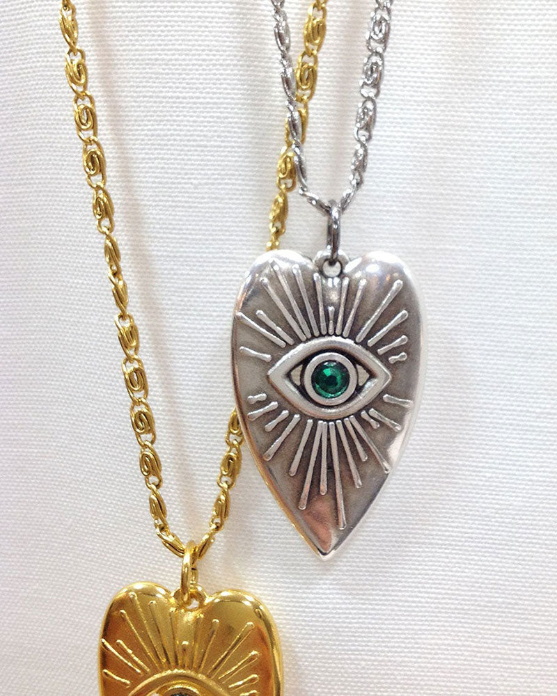 Evil eye heart pendant necklace adorned with an emerald Swarovski crystal in the middle of the eye and a long stainless steel chain.